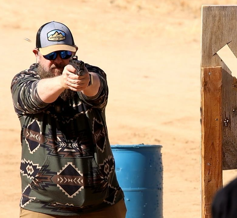 Shawn Herrin shooting a handgun during an outdoor range drill